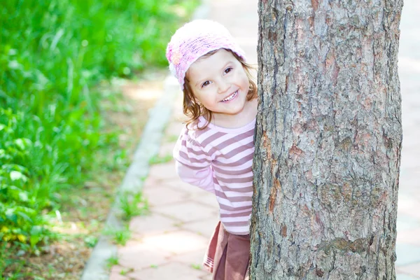 Little girl hiding behind a tree — Zdjęcie stockowe