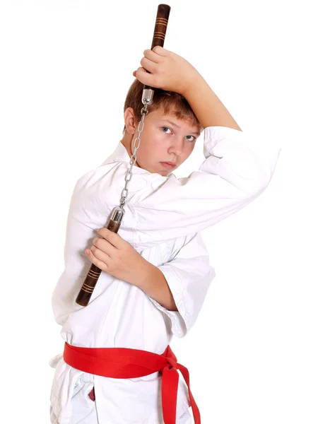 Подросток в кимоно делает упражнения боевых искусств с нунчаком Лицензионные Стоковые Фото