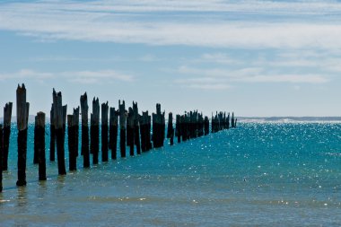 Beautiful rotten mooring on a beach where only the pillars are l clipart