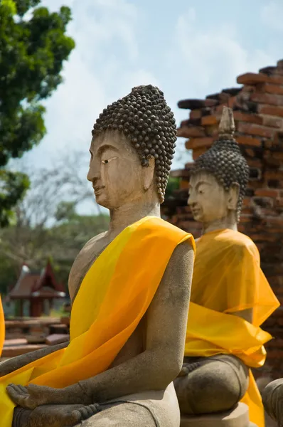 Дві статуї Будди, загорнуті в помаранчевий шарф. — стокове фото