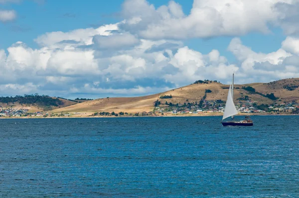 Luxus yacht vitorlák kék vizek egy nyári partvonal mentén — Stock Fotó