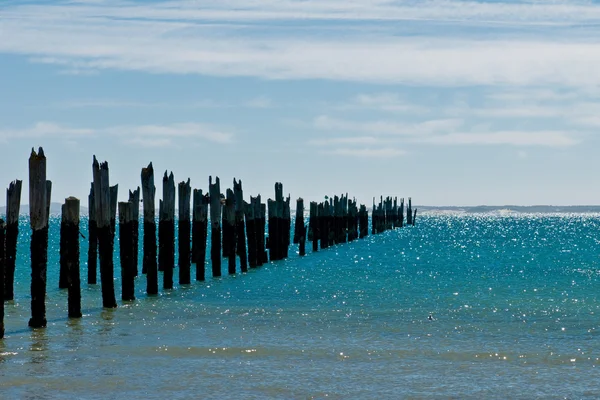 Beautiful rotten mooring on a beach where only the pillars are l — Stock Photo, Image