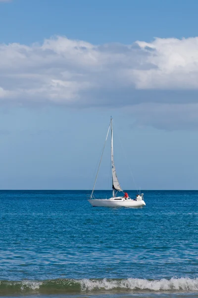 Белая яхта плывет в море вдоль береговой линии — стоковое фото