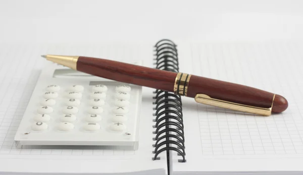 Penna e calcolatrice bianca sul blocco note a spirale — Foto Stock