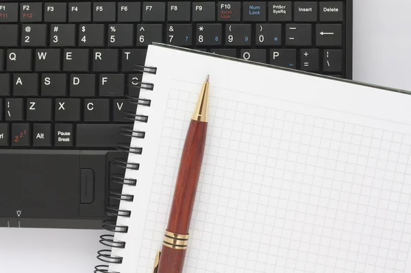 Stift und Spiralblock auf schwarzer Laptop-Tastatur — Stockfoto
