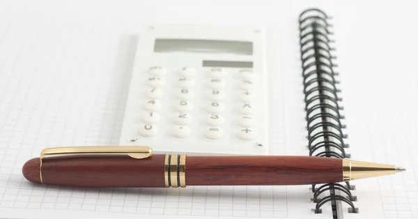 Pióra i biała kalkulator na notatnik spirala — Zdjęcie stockowe