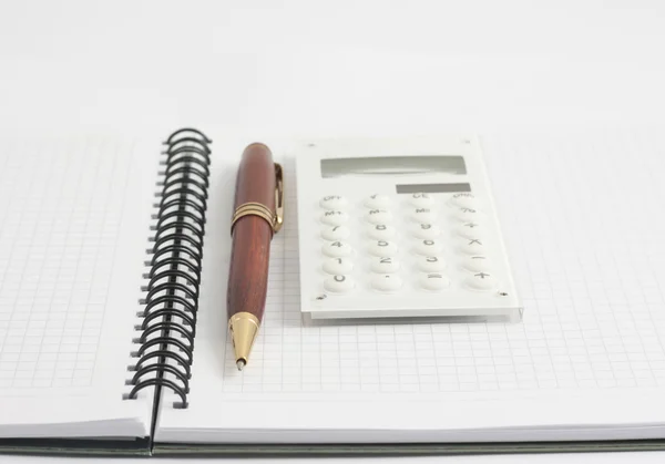 Pióra i biała kalkulator na notatnik spirala — Zdjęcie stockowe