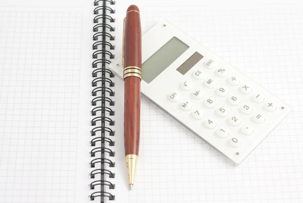 Penna e calcolatrice bianca sul blocco note a spirale, vista dall'alto — Foto Stock