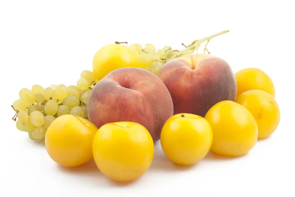 stock image Two peaches, yellow plums and grapes branch on white