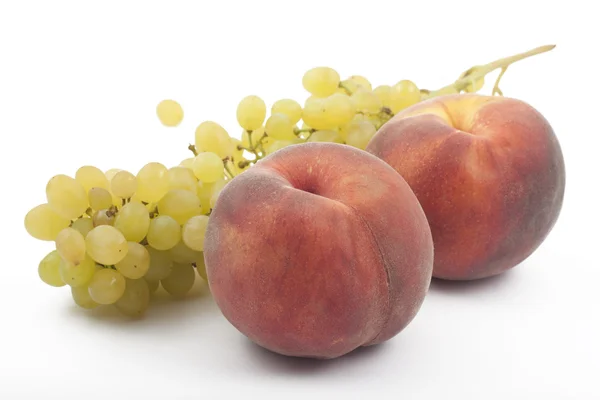 Два персика и виноградная ветвь на белом — стоковое фото