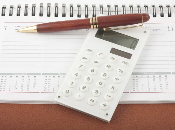 Ручка и калькулятор на открытом блокноте дневника — стоковое фото