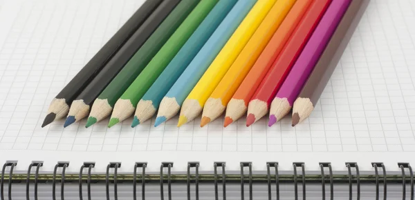 Crayons multicolores sur carnet spirale ouvert — Photo
