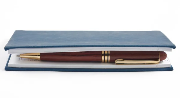 Ручка в закрытом голубом блокноте на белом — стоковое фото