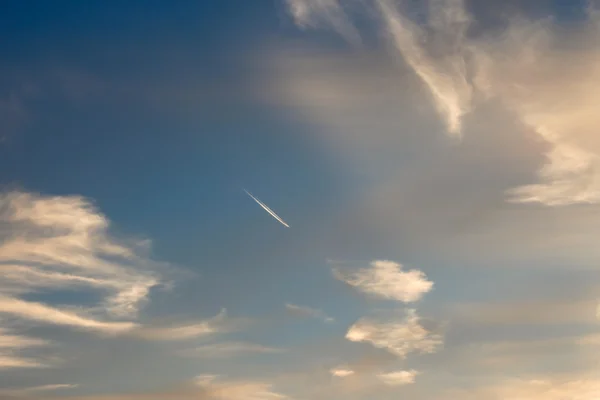 Flugzeuge zwischen Stratosphärenwolken bei Sonnenuntergang verfolgen — Stockfoto