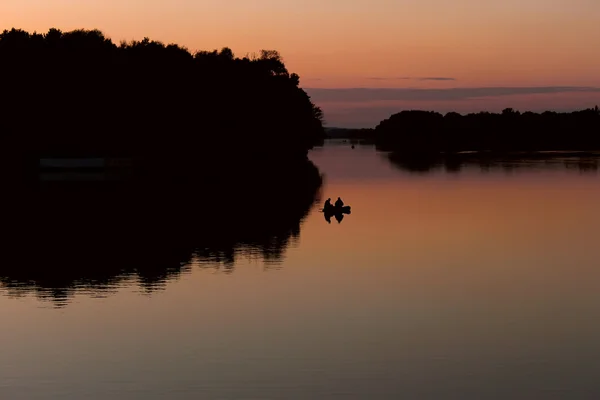 Pescadores em um barco flutuando no lago após o pôr do sol — Fotografia de Stock