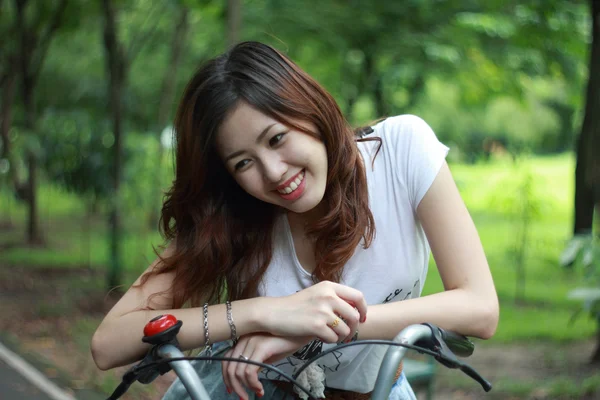 Mujer con una bicicleta al aire libre sonriendo — Foto de Stock