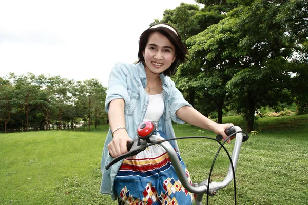 Γυναίκα με ένα ποδήλατο που είναι χαμογελώντας σε εξωτερικούς χώρους — Φωτογραφία Αρχείου
