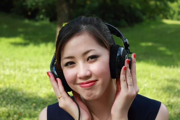 Beautiful girl listening music in the park — Stock Photo, Image
