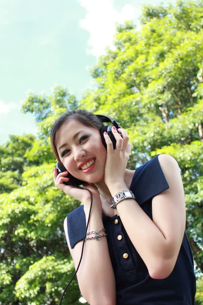 Hermosa chica escuchando música en el parque Imagen de stock