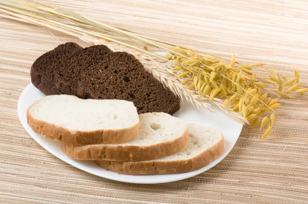 Вирізати чорний і білий хліб на тарілці — стокове фото