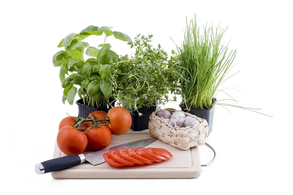 Ervas aromáticas com tábua de cortar de tomate e alho — Fotografia de Stock