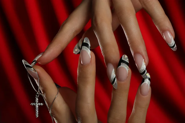 Ruce mladé ženy s pěkně manicure.on červeném pozadí — Stock fotografie