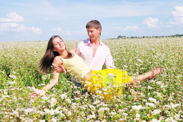 Jovem casal encantador jogando em um campo de flores — Fotografia de Stock