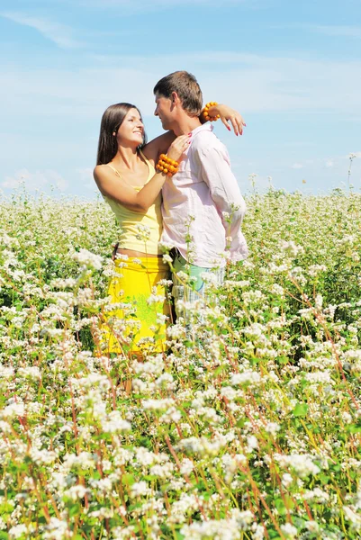 Casal jovem que joga no campo de flores em dia ensolarado — Fotografia de Stock