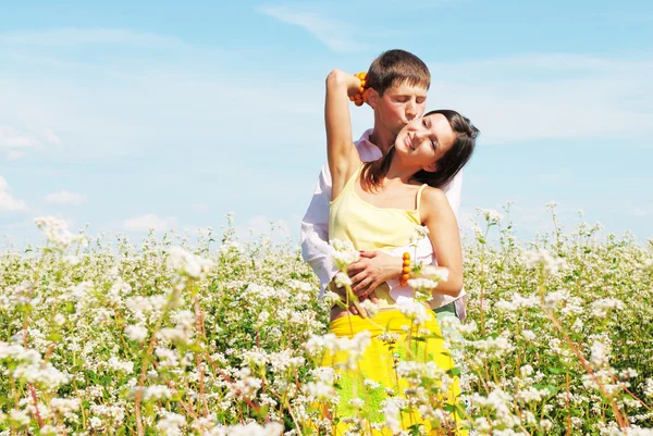 Güneşli bir günde çiçek sahada oynayan genç Çift — Stok fotoğraf