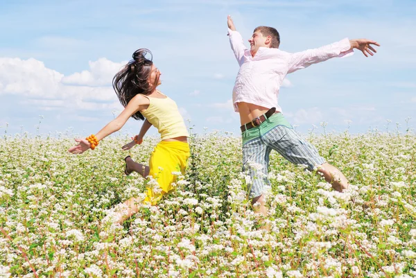 Young couple playing on field of flowers in sunny day — Stock Photo, Image