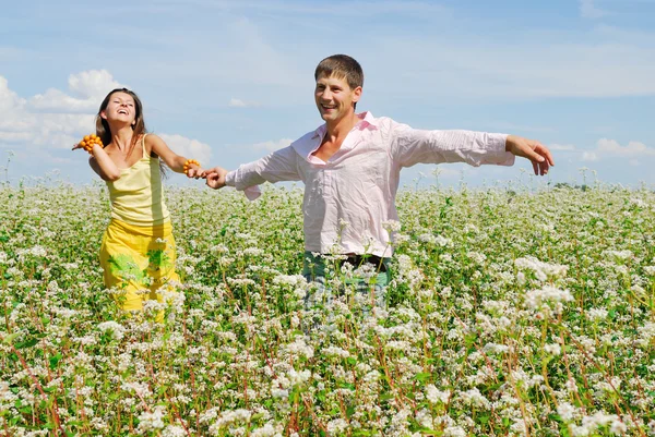 Jeune couple sur champ de fleurs — Photo