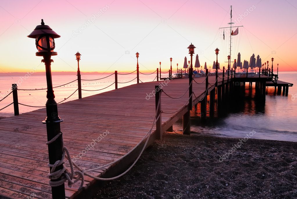 Wooden pier lighted by pink sunrise glow