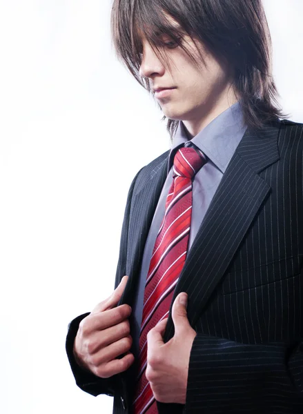 Jeune homme d'affaires aux cheveux longs, redresse sa veste . Photo De Stock