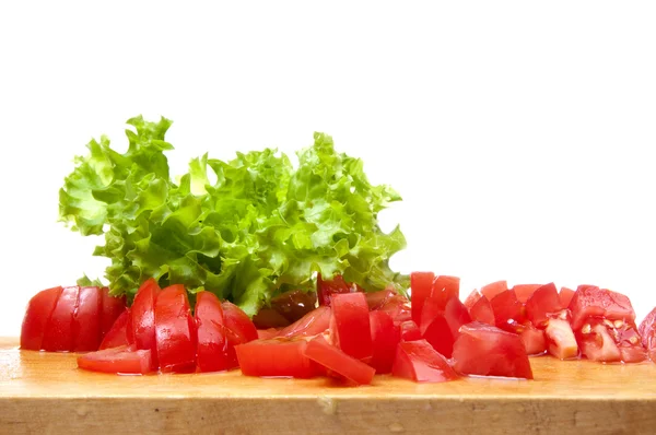 stock image Sliced tomatoes and the fresh lettuce on the board