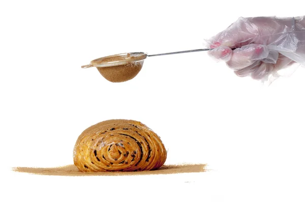 Strewing a bun with cinnamon — Stock Photo, Image
