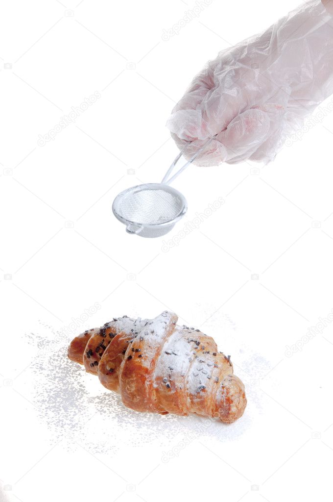 Strewing a croissant powdered sugar