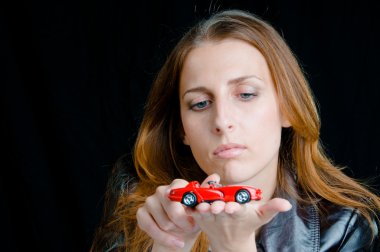 Hot girl playing with a model of the red sport car. clipart