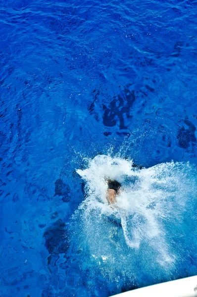 Человек ныряет в море с яхтенной доски — стоковое фото