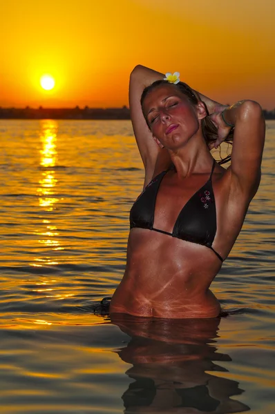La muchacha hermosa se relaja en la puesta del sol en las ondas del mar rojo —  Fotos de Stock