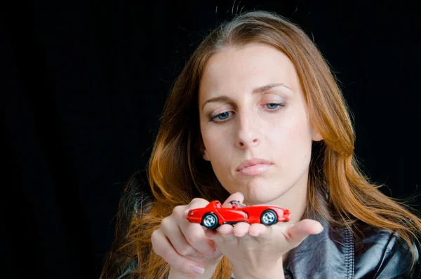 Stock image Hot girl playing with a model of the red sport car.