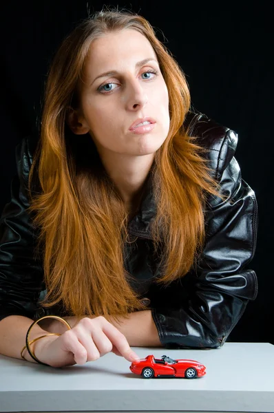 Stock image Hot girl playing with a model of the red sport car.