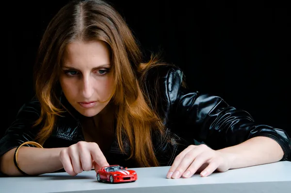 Stock image Hot girl playing with a model of the red sport car.