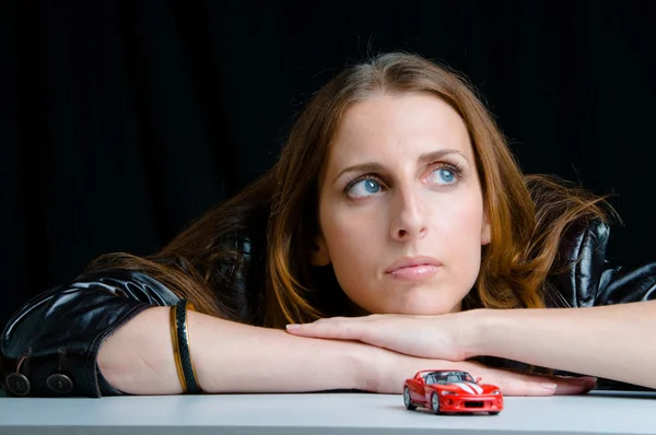 Heiße Mädchen spielen mit einem Modell des roten Sportwagens. — Stockfoto
