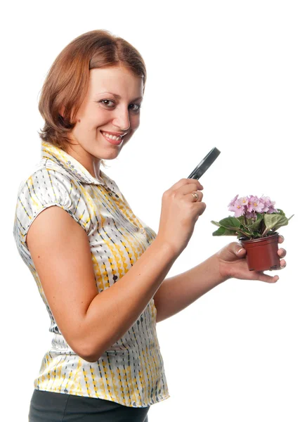 Smiling girl considers violets through a magnifier — Stock Photo, Image