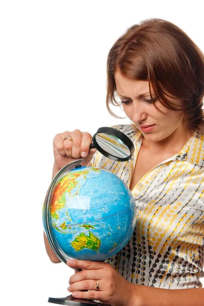 Girl attentively examines the globe through a magnifier — Stock Photo, Image