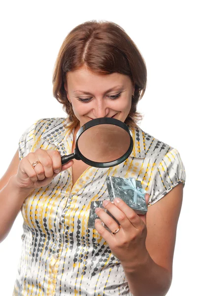 Girl looks at a gift through a magnifier — Stock Photo, Image