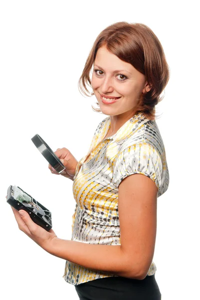 Smiling girl considers hard driver through a magnifier — Stock Photo, Image