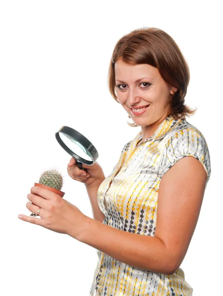 Smiling girl considers a cactus through a magnifier — Stock Photo, Image