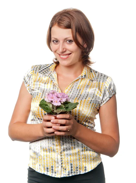 Menina sorridente com violetas em um vaso de flores — Fotografia de Stock