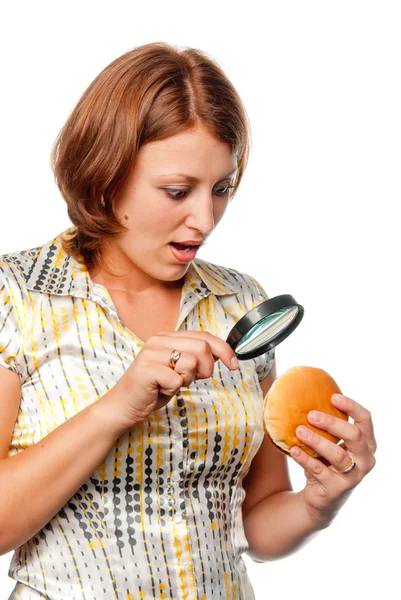 Surprised girl considers a hamburger through a magnifier — Stock Photo, Image